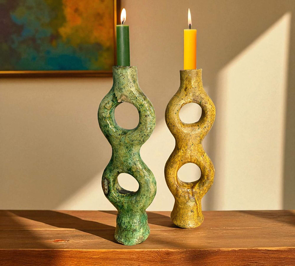 Two unique candle holders with candles on a wooden surface, with a neutral background.