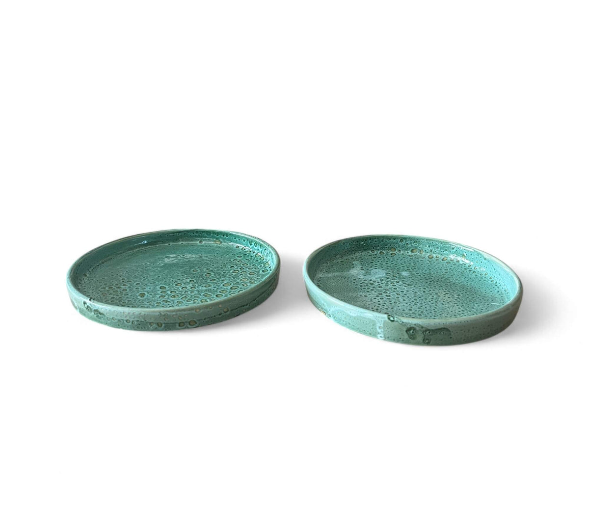 Two green ceramic plates on a white background