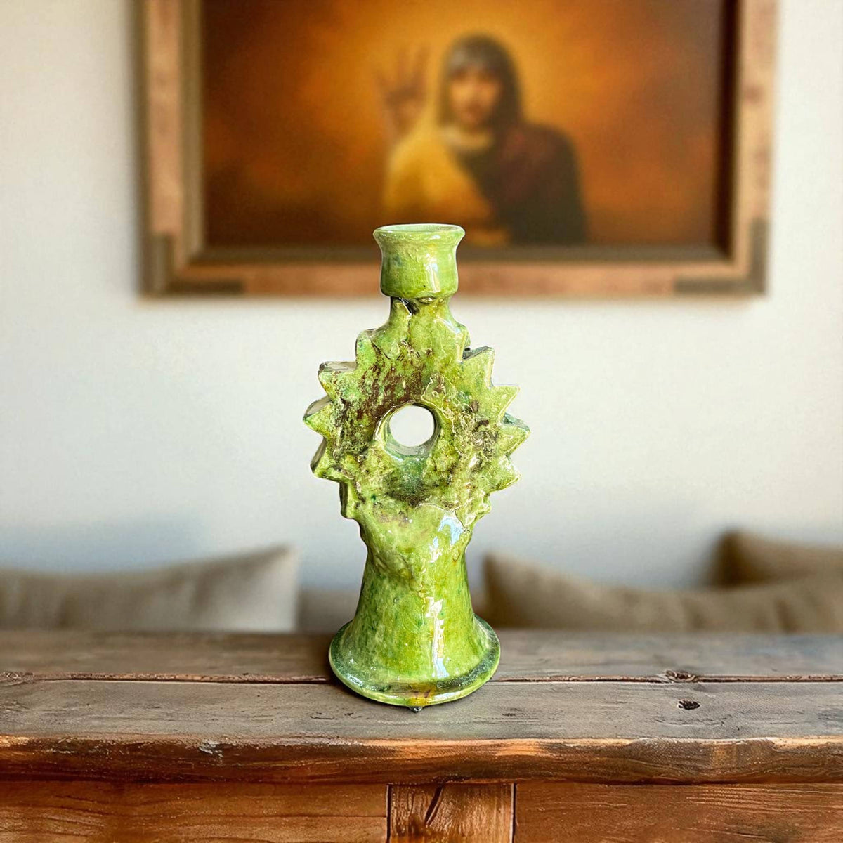 Green ceramic candle holder on a wooden surface with a blurred portrait in the background