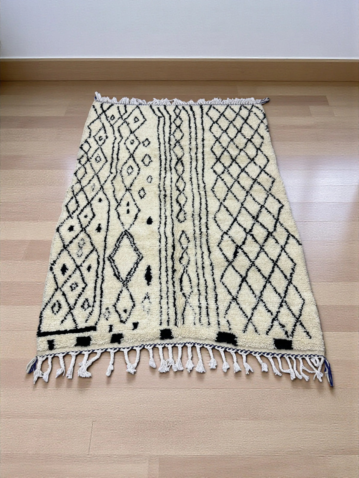 Handwoven Moroccan Azilal carpet in ivory wool with black diamond patterns and fringe, 223 × 156 cm
