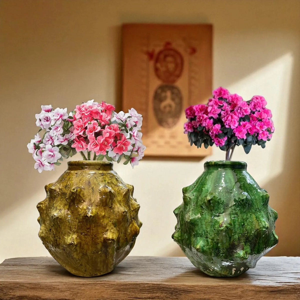 Two decorative vases with floral arrangements on a wooden surface, with a blurred background.