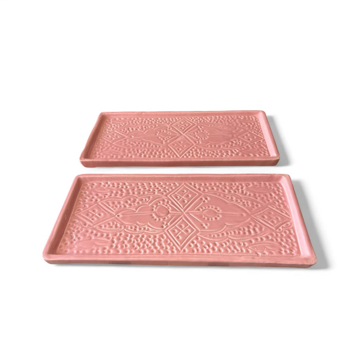 Two pink trays with decorative patterns on a white background