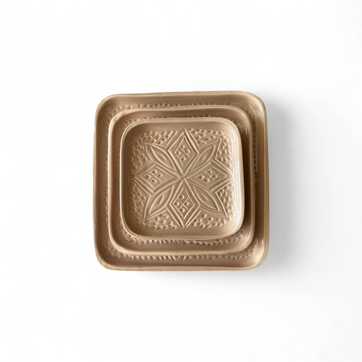Bronze-colored square dish with embossed design on a white background