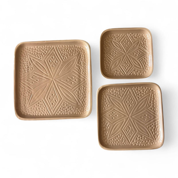 Set of three square ceramic plates with geometric patterns on a white background