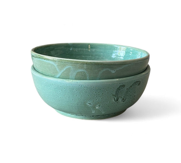 Two teal ceramic bowls stacked on a white background