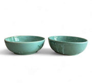 Two teal ceramic bowls on a white background