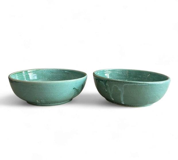 Two teal ceramic bowls on a white background