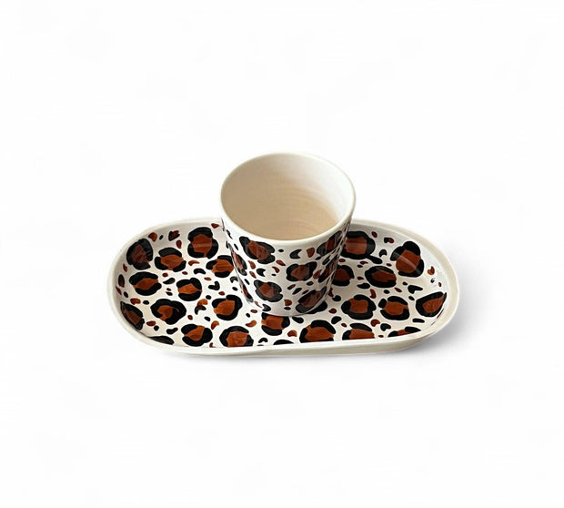 Ceramic cup and saucer with leopard print design on a white background