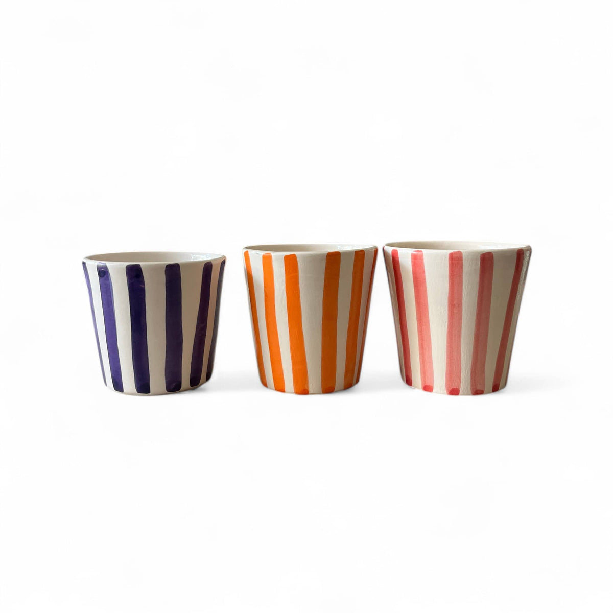 Three ceramic cups with striped patterns on a white background