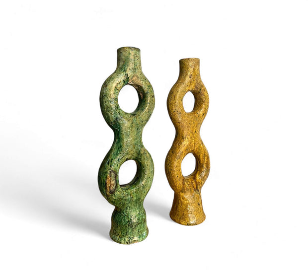 Two twisted ceramic vases, one green and one brown, on a white background