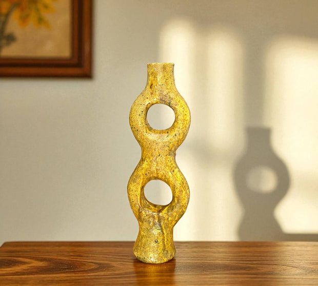 Decorative yellow vase with circular design on a wooden surface