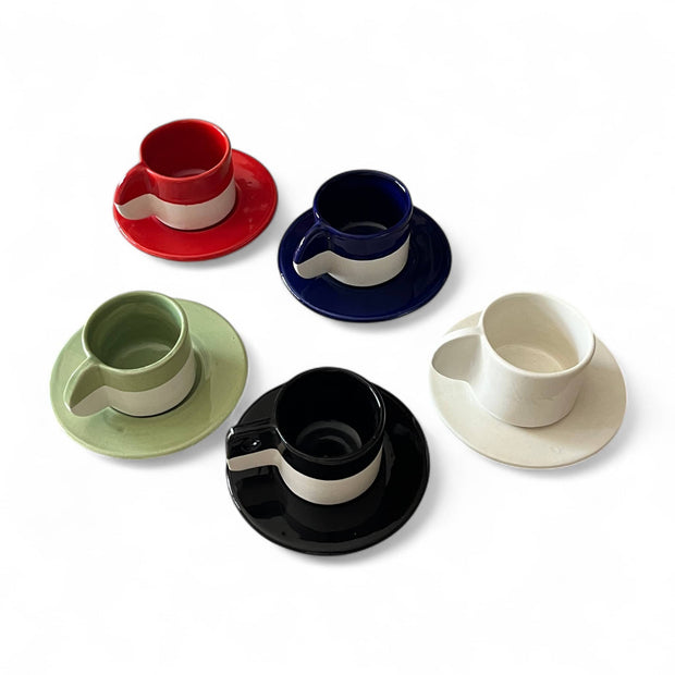 Set of five ceramic cups and saucers in red, blue, green, black, and white on a white background.