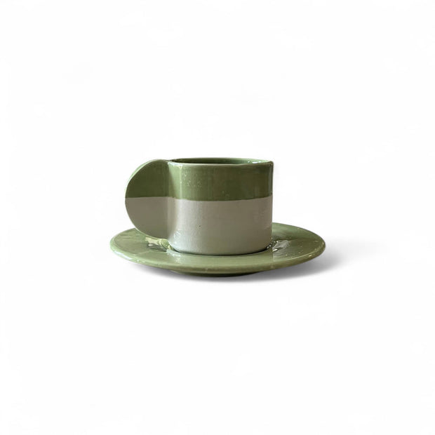 Green ceramic cup and saucer on a white background