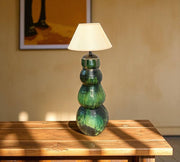 Green ceramic table lamp with a white shade on a wooden surface.