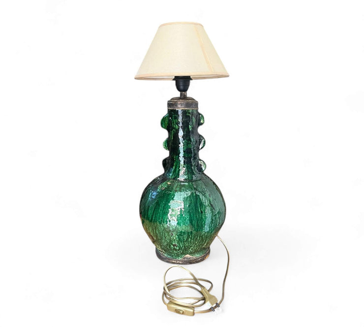 Green ceramic table lamp with a beige lampshade on a white background