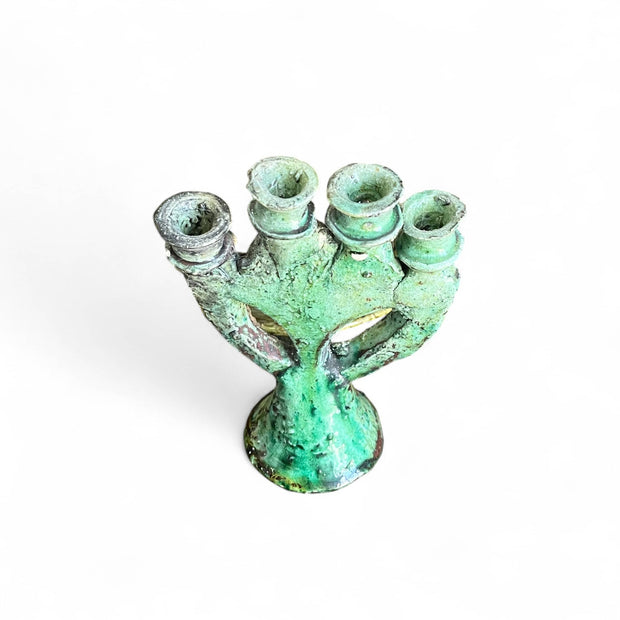 Green ceramic candle holder with four small candles on a white background