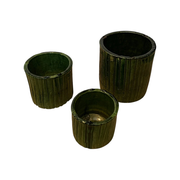 Three dark green cylindrical planters with ribbed texture on a white background