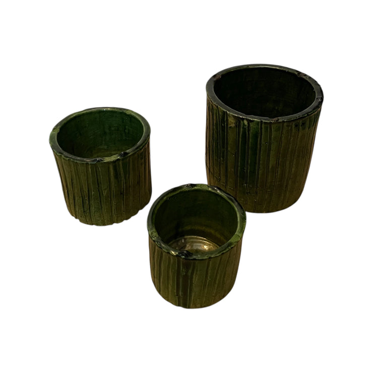 Three dark green cylindrical planters with ribbed texture on a white background