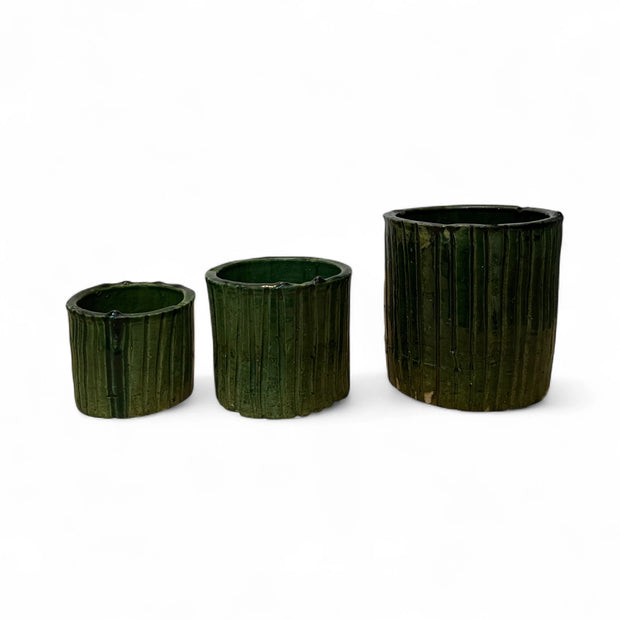 Three dark green ceramic pots of varying sizes on a white background