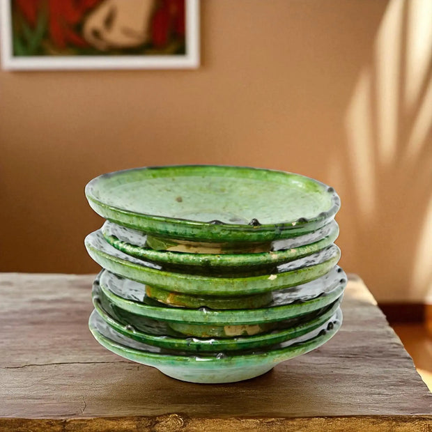 Stack of green ceramic plates on a wooden surface with a blurred background