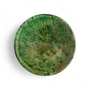 Round green ceramic object with a textured surface on a white background