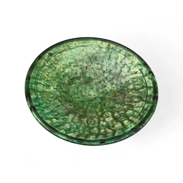 Green ceramic plate with a textured surface on a white background