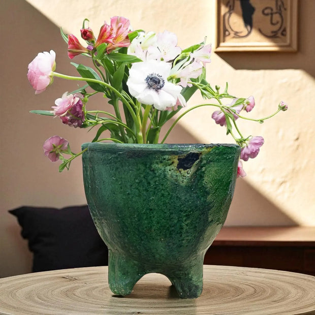 Green ceramic vase with flowers on a wooden surface