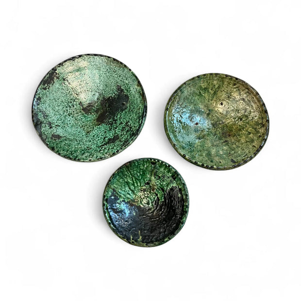 Three green ceramic plates with a textured surface on a white background