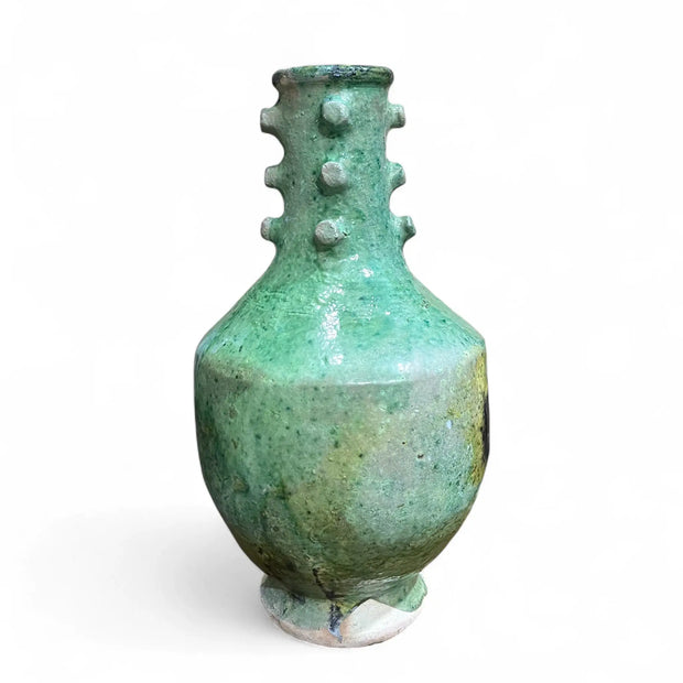 Green ceramic vase with textured surface on a white background