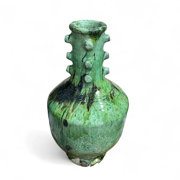 Green ceramic vase with textured surface on a white background