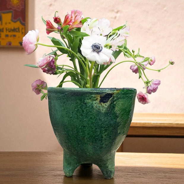 Green ceramic vase with flowers on a wooden surface