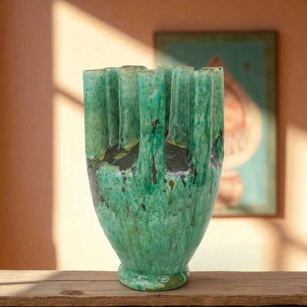 Green ceramic vase on a wooden surface with a blurred background