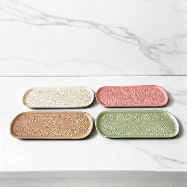 Four ceramic trays in different colors on a marble surface