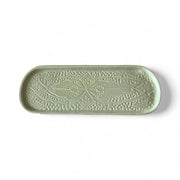 Green ceramic tray with decorative patterns on a white background
