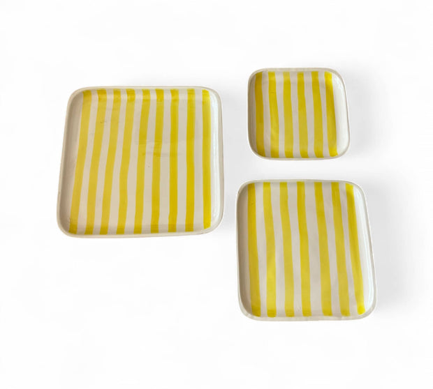 Set of three square ceramic dishes with yellow and white striped pattern on a white background