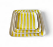 Set of three square trays with yellow and white striped pattern on a white background