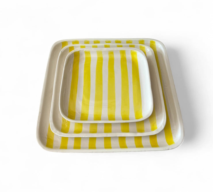 Set of three square trays with yellow and white striped pattern on a white background