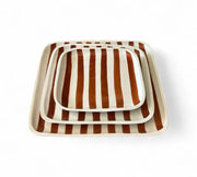 Set of three striped trays with brown and white stripes on a white background