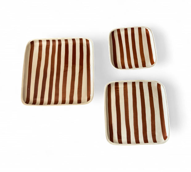 Set of three square ceramic plates with brown and beige vertical stripes on a white background