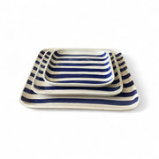 Set of three striped ceramic trays with blue and white stripes on a white background