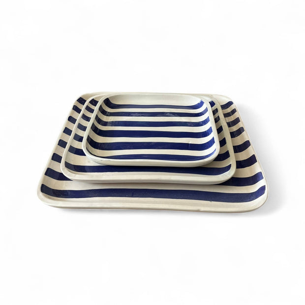 Set of three striped ceramic trays with blue and white stripes on a white background