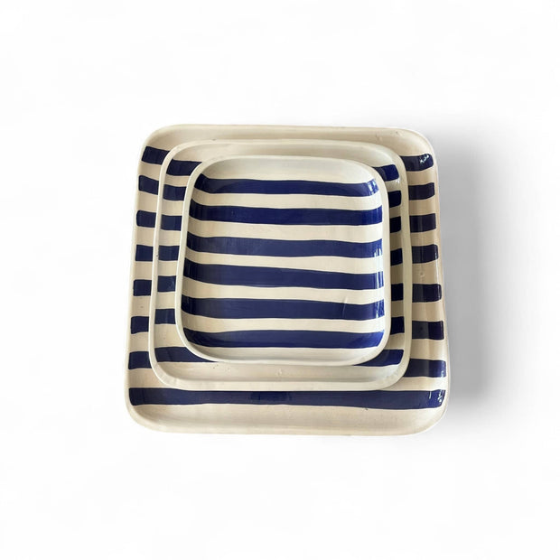 Set of three square ceramic trays with blue and white stripes on a white background