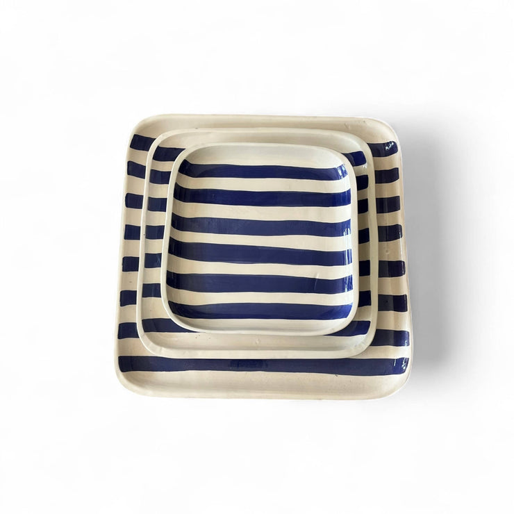Set of three square ceramic trays with blue and white stripes on a white background