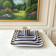 Blue and white striped ceramic set on a table with a garden painting in the background