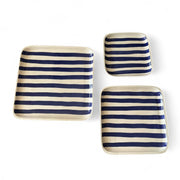 Set of three square ceramic plates with blue and white stripes on a white background