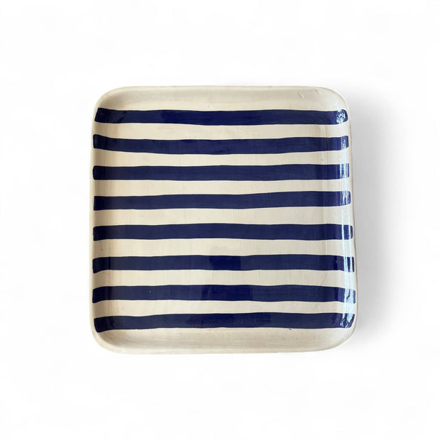 Rectangular ceramic tray with blue and white stripes on a white background