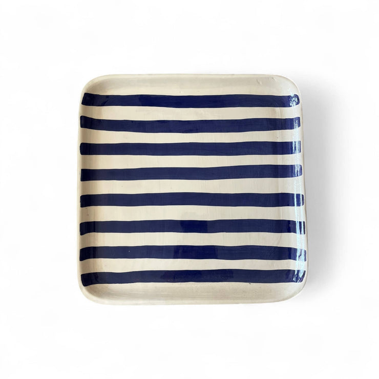 Rectangular ceramic tray with blue and white stripes on a white background