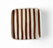 Square ceramic plate with brown and white vertical stripes on a white background