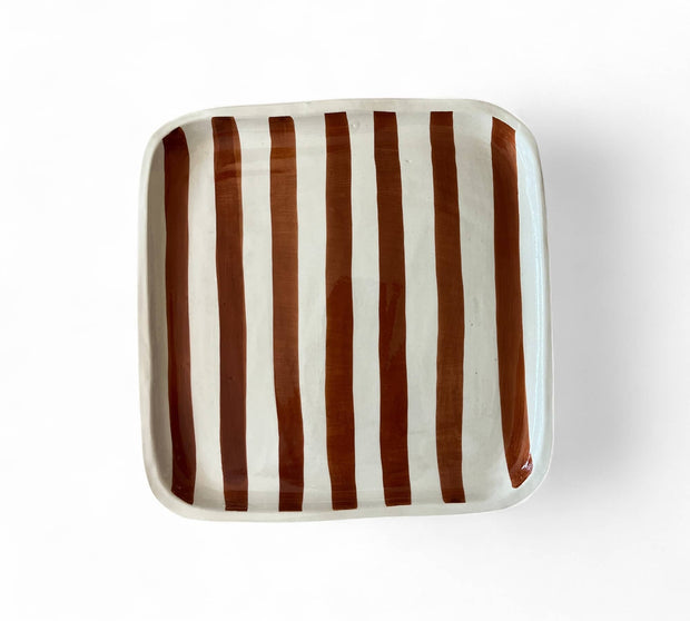 Square ceramic plate with brown and white vertical stripes on a white background