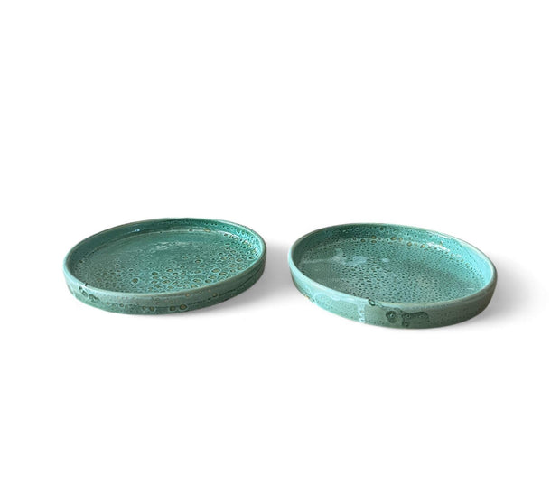 Two green ceramic plates on a white background